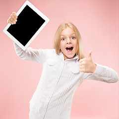 Image showing Little funny girl with tablet on pink background