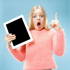 Image showing Little funny girl with tablet on blue background