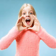 Image showing Isolated on blue young casual teen girl shouting at studio