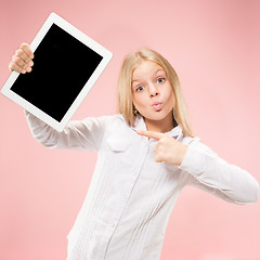 Image showing Little funny girl with tablet on pink background