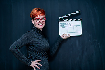 Image showing redhead woman holding movie clapper