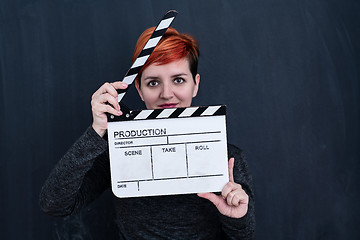 Image showing redhead woman holding movie clapper