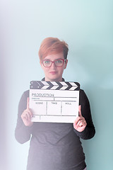 Image showing woman holding movie clapper against cyan background