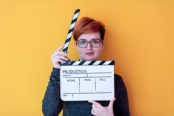 Image showing woman holding movie clapper against yellow background
