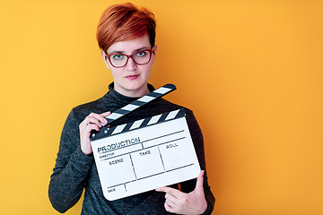 Image showing woman holding movie clapper against yellow background