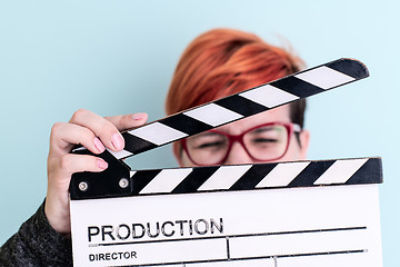 Image showing woman holding movie clapper against cyan background