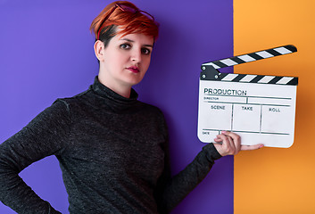 Image showing woman holding movie clapper against colorful background