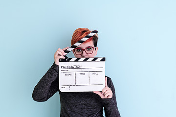 Image showing woman holding movie clapper against cyan background