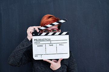 Image showing redhead woman holding movie clapper