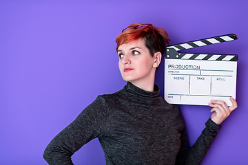 Image showing woman holding movie clapper against purple background