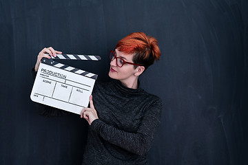 Image showing redhead woman holding movie clapper