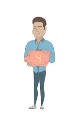 Image showing Young hispanic businessman holding a piggy bank.