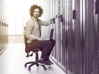 Image showing engineer working on a laptop in server room