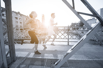 Image showing young couple jogging across the bridge in the city