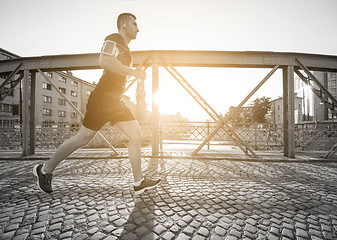 Image showing man jogging across the bridge at sunny morning