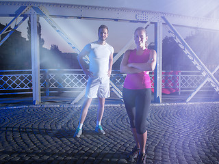 Image showing portrait of couple jogging across the bridge in the city