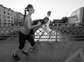 Image showing young couple jogging across the bridge in the city