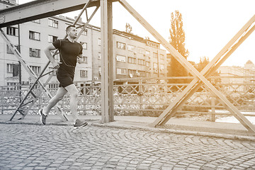 Image showing man jogging across the bridge at sunny morning