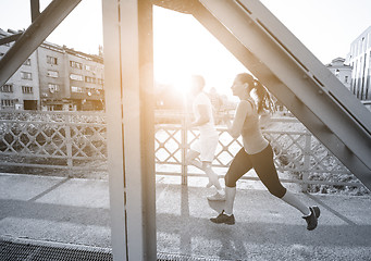 Image showing young couple jogging across the bridge in the city