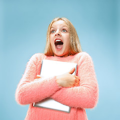 Image showing Teen girl with laptop. Love to computer concept. Attractive female half-length front portrait, trendy blue studio backgroud.