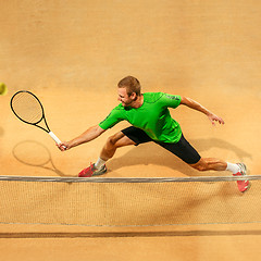 Image showing The one jumping player, caucasian fit man, playing tennis on the earthen court