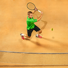 Image showing The one jumping player, caucasian fit man, playing tennis on the earthen court