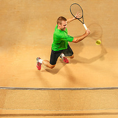 Image showing The one jumping player, caucasian fit man, playing tennis on the earthen court