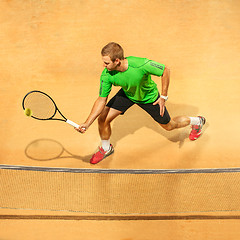 Image showing The one jumping player, caucasian fit man, playing tennis on the earthen court