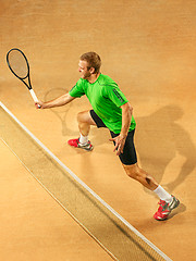 Image showing The one jumping player, caucasian fit man, playing tennis on the earthen court