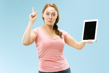 Image showing Portrait of a confident casual girl showing blank screen of laptop isolated over blue background