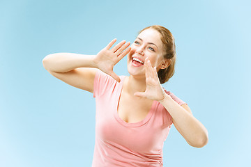 Image showing Isolated on blue young casual woman shouting at studio