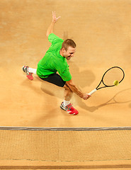 Image showing The one jumping player, caucasian fit man, playing tennis on the earthen court