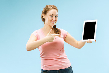 Image showing Portrait of a confident casual girl showing blank screen of laptop isolated over blue background