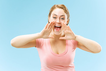 Image showing Isolated on blue young casual woman shouting at studio