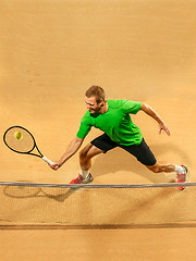 Image showing The one jumping player, caucasian fit man, playing tennis on the earthen court