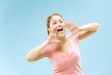 Image showing Isolated on blue young casual woman shouting at studio