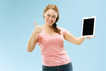 Image showing Portrait of a confident casual girl showing blank screen of laptop isolated over blue background