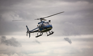 Image showing Blue helicopter in flight over gray sky