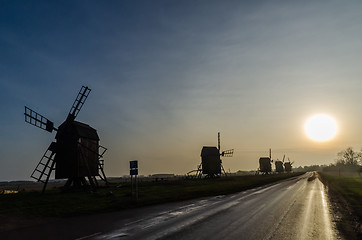 Image showing Windmill silhouettes by roadside