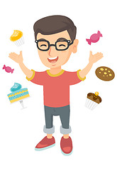 Image showing Happy caucasian boy standing among lots of sweets.