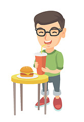 Image showing Little boy drinking soda and eating cheeseburger.