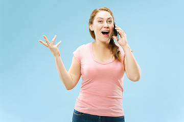 Image showing Young beautiful woman using mobile phone studio on blue color background