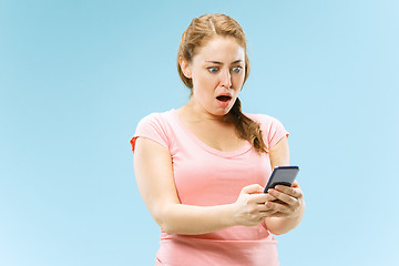 Image showing Young beautiful woman using mobile phone studio on blue color background