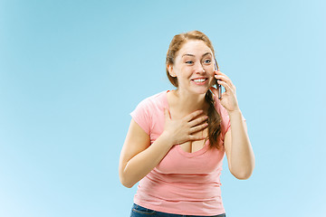 Image showing Young beautiful woman using mobile phone studio on blue color background