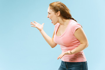 Image showing Beautiful female half-length portrait isolated on blue studio backgroud. The young emotional surprised woman