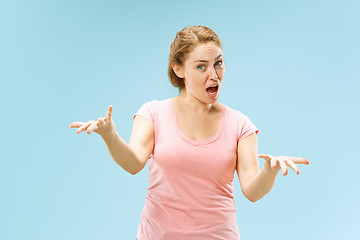 Image showing Beautiful female half-length portrait isolated on blue studio backgroud. The young emotional surprised woman