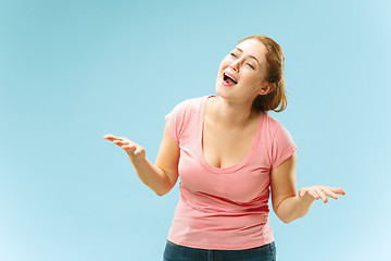 Image showing Beautiful female half-length portrait isolated on blue studio backgroud. The young emotional surprised woman