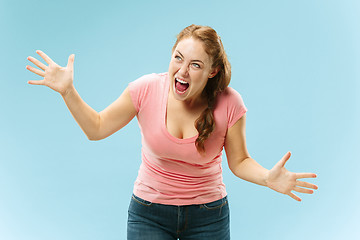 Image showing The young emotional angry woman screaming on blue studio background