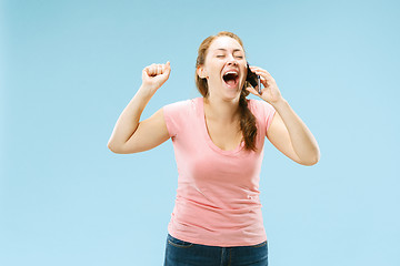 Image showing Young beautiful woman using mobile phone studio on blue color background