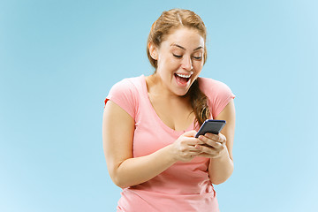 Image showing Young beautiful woman using mobile phone studio on blue color background